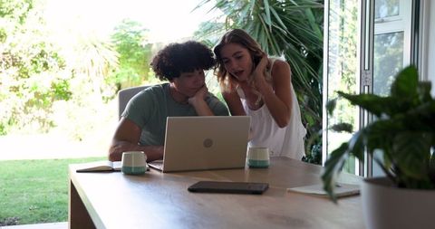 Young Couple Collaborating on Laptop at Home Office with Greenery