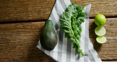Overhead View of Fresh Avocado, Kale, and Lime on Rustic Wooden Surface