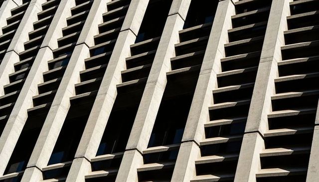Brutalist concrete facade repeating vertical piers with angular horizontal sunshades