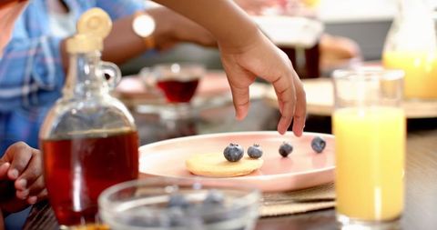 Child Reaching for Blueberries During Family Brunch