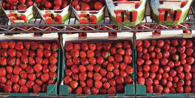Bright red strawberries in green baskets shown at a farmers market. Perfect for promoting fresh produce, healthy eating, summer fruit, or organic farm goods.