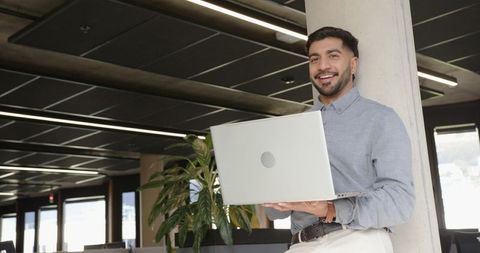 Professional Man Holding Laptop in Modern Office Setting