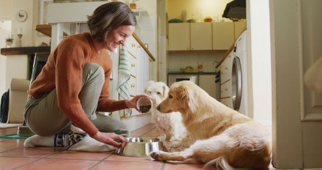 Smiling caucasian woman feeding her pet dogs pouring food into bowl in kitchen at home - Download Free Stock Photos Pikwizard.com