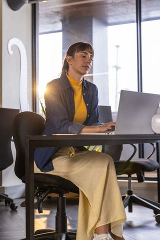 Businesswoman typing on laptop in a modern office setting