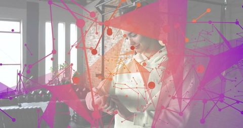 Holding tablet and tapping screen in sunlit loft with magenta geometric network overlay