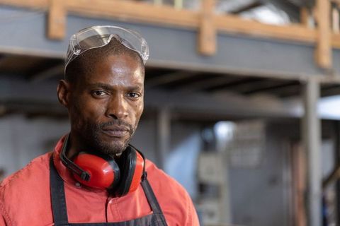 African american fabrication worker wearing safety goggles and earmuffs in workshop