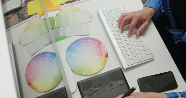 Graphic designer at work in a modern office, with copy space. Color swatches and digital tools suggest a creative design process.