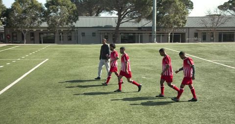 Soccer Players Practicing on Sunny Field with Coach