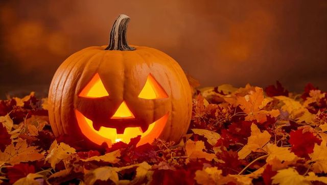 Glowing jack-o'-lantern among autumn leaves