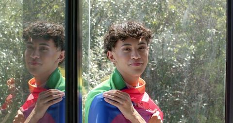 Young Man Reflecting Outdoors with Pride Flag in Urban Setting