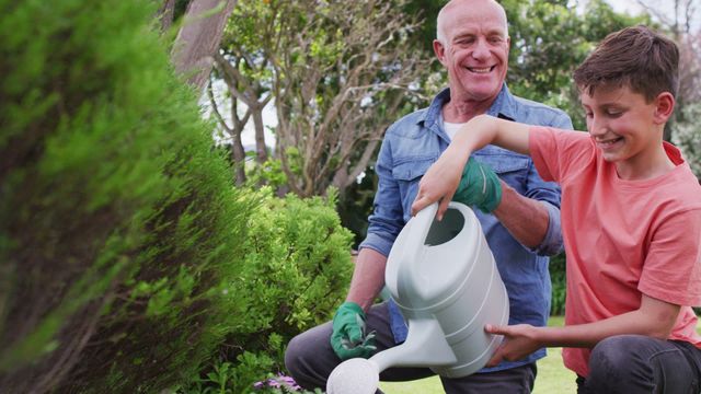 Grandfather and grandson enjoying time together while watering plants in a garden on a sunny day. Perfect for illustrating family bonding, outdoor activities, gardening tutorials, and home life commercial use.