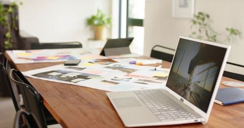 Creative workspace with laptop, mockups, sticky notes on wood table for team brainstorming