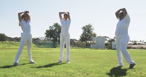 Female Athletes Stretching Before Game on Sunny Cricket Field