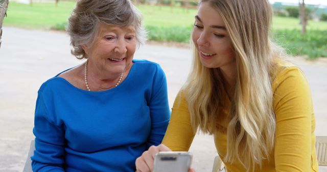 Young Woman Teaching Elderly Lady to Use Smartphone Outdoors - Download Free Stock Photos Pikwizard.com