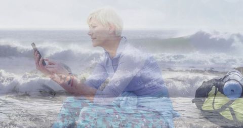 Mature woman sitting checking phone on shore carrying backpack and yoga mat double exposure