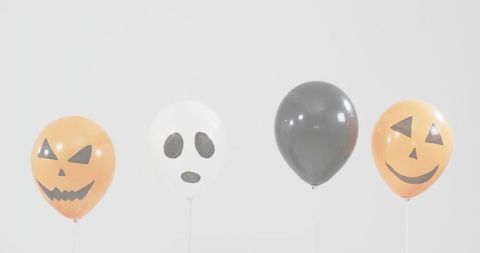 Floating halloween balloons in row with jack-o'-lantern and ghost faces for minimal decor