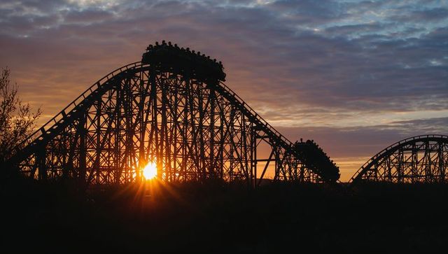 Dramatic silhouette of wooden roller coaster at sunset