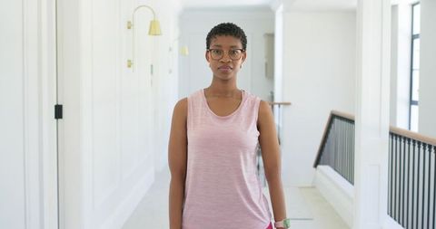 African american woman standing in bright modern hallway wearing glasses and smartwatch