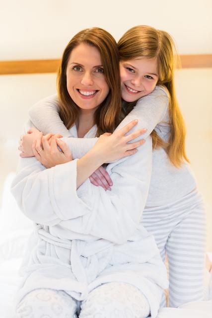 Portrait of mother and daughter embracing each other in bedroom at home