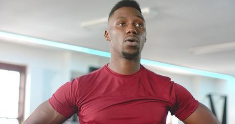 Focused african american athlete training in bright gym wearing maroon athletic shirt