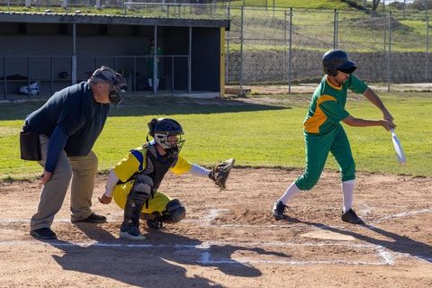 Baseball batter swinging as catcher reaching and umpire observing home plate action