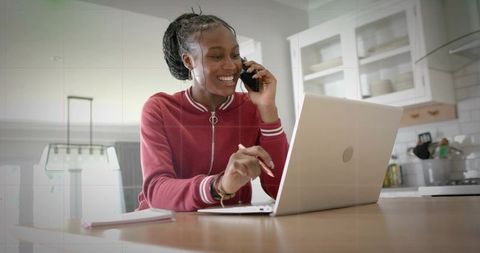 Woman Using Smartphone and Laptop in Home Office Setup