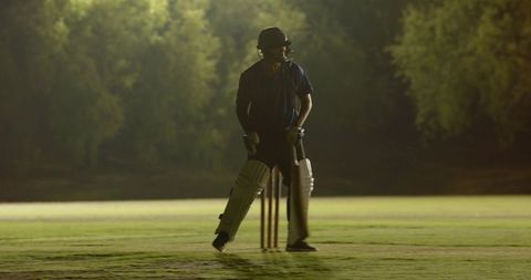 Night cricket batsman losing grip retrieving bat after facing incoming delivery at stumps