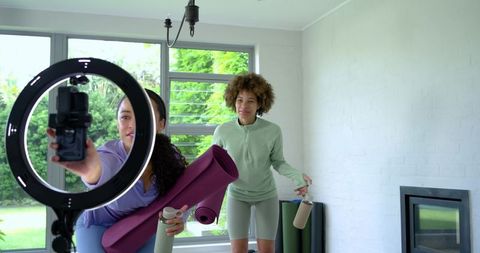African american women preparing ring light and yoga mats for home fitness content