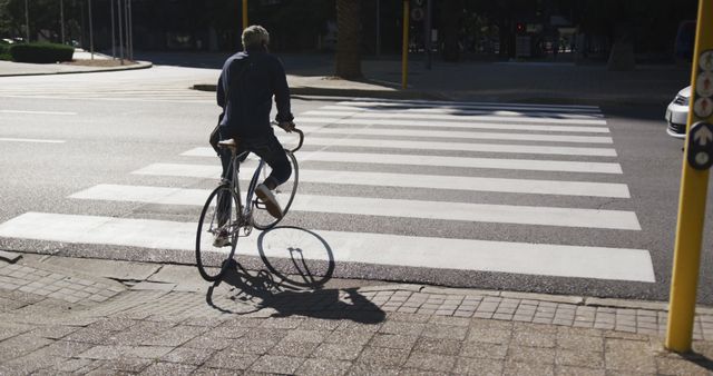 Rear view of african american senior man riding bicycle crossing the road. active senior lifestyle living concept