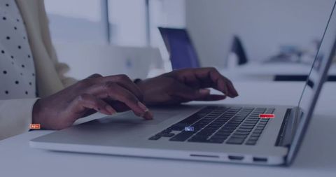Professional Woman Typing at Office Desk with Silver Laptop