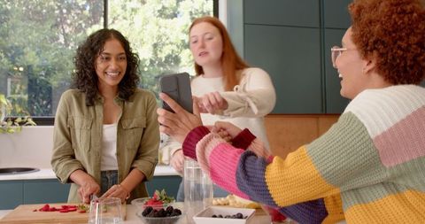 Women Enjoying Culinary Activity with Fresh Berries in Bright Kitchen