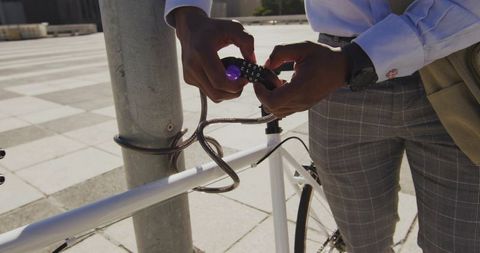 Businessman locking bicycle in urban area with cable lock