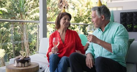 Senior Couple Celebrating Milestone with Wine on Balcony