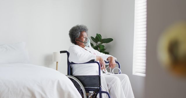 Elderly woman sitting in wheelchair by window wearing mask - Download Free Stock Images Pikwizard.com