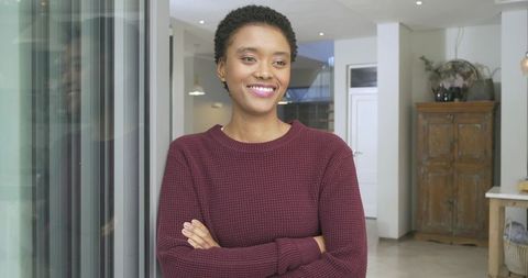 Smiling Woman Relaxing at Home by Glass Door in Cozy Sweater