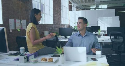 Woman offering coffee and pastry in modern open-plan office