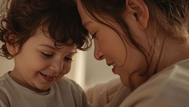 Mother leaning close with preschool son sharing tender smile and warm embrace on sofa