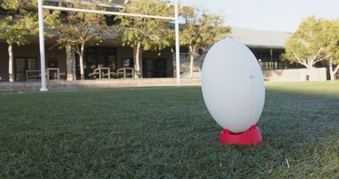 Rugby Ball on Kicking Tee by Goalposts on Artificial Turf