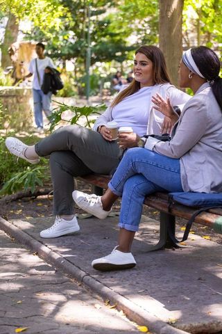 African american friends chatting on park bench holding coffee cups