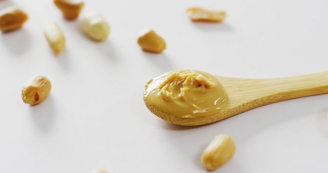 Close Up of Creamy Peanut Butter on Wooden Spoon with Scattered Nuts - Download Free Stock Images Pikwizard.com