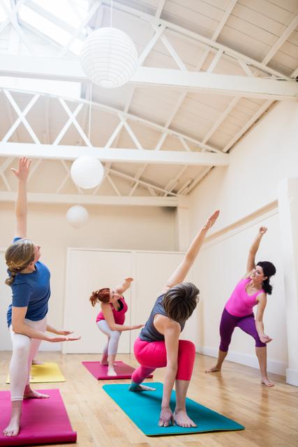 Ideal for promoting fitness classes, wellness programs, and healthy lifestyle campaigns. Useful for illustrating group exercise dynamics, personal training, and yoga practice in a bright, modern studio setting.