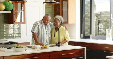 Senior couple enjoying meal in bright kitchen with balloons