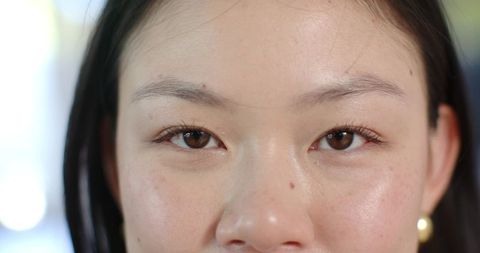 Close-up chinese woman showing natural skin texture and mole, direct gaze beauty portrait