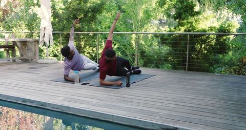 Diverse Male Friends Exercising Together in Side Plank Pose on Sunny Deck