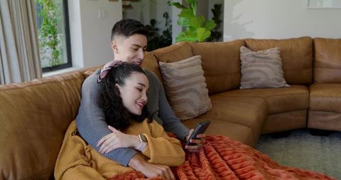 Couple relaxing under blanket on cozy leather sofa