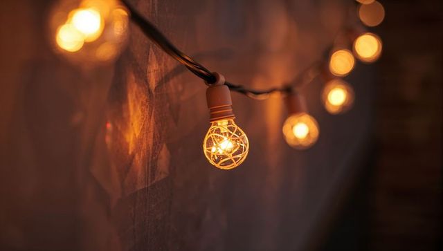 Amber Globe String Lights Hanging Against Textured Wall Glowing Filament Bokeh Ambience