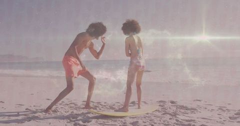 Playful Friends Practicing Surfing on Sunny Shoreline