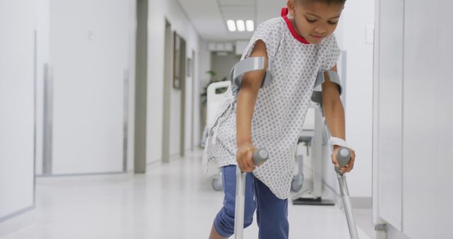 African american male doctor walking with child patient using crutches at hospital - Download Free Stock Photos Pikwizard.com
