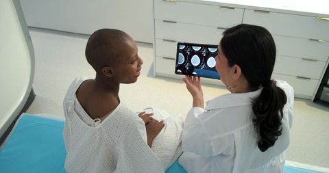 Female clinician reviewing brain scans with smiling black patient during clinic consultation