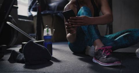 Athletic Woman Taking Break in Gym Using Smartphone